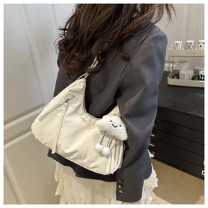White nylon shoulder bag with cute cloud charm shown on a model in gray blazer