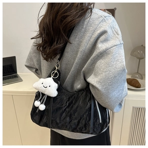 Detail of black wrinkled texture shoulder bag with metal zipper and cloud plush charm