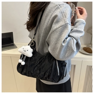 Detail of black wrinkled shoulder bag with cloud plush keychain in a minimalist setting