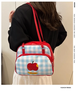Detail of red apple motif and blue checkered canvas on this trendy shoulder bag