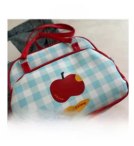 Detail view of plaid shoulder bag with red apple motif and contrast leather piping
