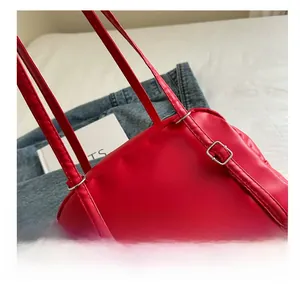Close-up of the bright red leather shoulder strap with a silver adjustable buckle detail