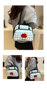 Detail of blue and white checkered pillow bag with red apple print and black straps