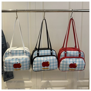 Detailed view of checkered blue handbags featuring red apple prints and contrast handles