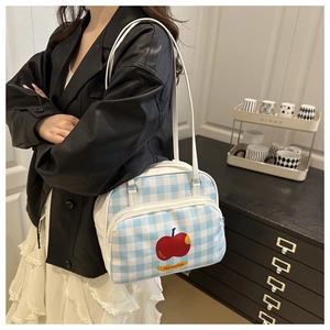 Detailed view of blue and white checkered tote bag with a red apple print and zipper pocket
