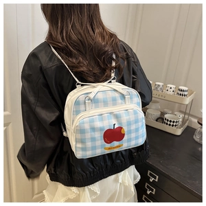 Detail of blue and white plaid backpack featuring cute red apple print and double zippers