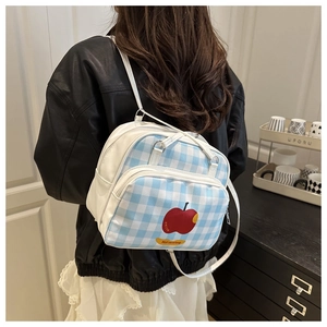 Detail of blue and white gingham bag featuring a vibrant red apple print and adjustable strap