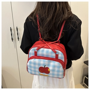 Detail of red leather backpack with blue checkered pocket and red apple print design