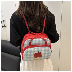Close-up of red leather and blue plaid backpack with apple pattern on the back