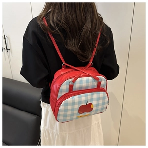 Detail of red backpack with blue checkered front pocket and cute apple print design
