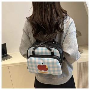 Detail of blue and white checkered backpack featuring red apple print and zipper pockets