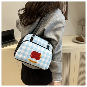 Detail shot of blue and white checkered tote bag with red apple motif on shoulder