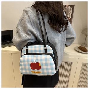 Detail of blue and white checkered tote bag with red apple print in daily use scene