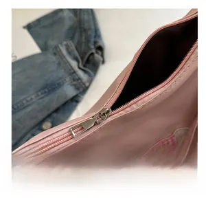 Close-up of smooth silver zipper and rabbit embroidery on pink leather tote bag