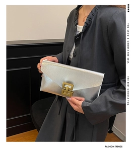 Detail of silver envelope clutch with metallic texture and gold geometric buckle lock