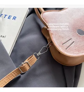 Detail of silver metal buckles and brown leather strap on pink suede cat handbag