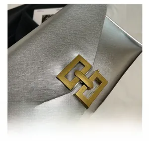 Detail shot of golden rectangular metal buckle on silver Saffiano leather clutch bag