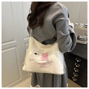 Detail of cream-colored tote bag featuring a plush puppy patch and large side pockets