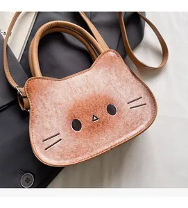 Close-up of a brown cartoon cat handbag with adjustable strap on a grey suit jacket