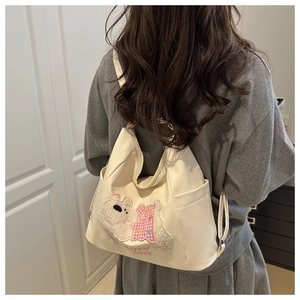 Rear view of model wearing a beige canvas puppy backpack with Happy Puppy embroidery