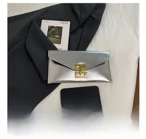 Detail showing metallic textured silver envelope clutch bag with golden geometric clasp
