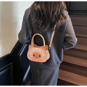 Detailed view of brown cat-shaped crossbody bag with plush texture and cartoon face details