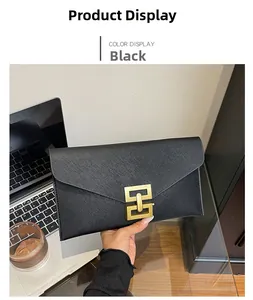 Close-up of black Saffiano leather envelope clutch bag with gold geometric lock in office setting