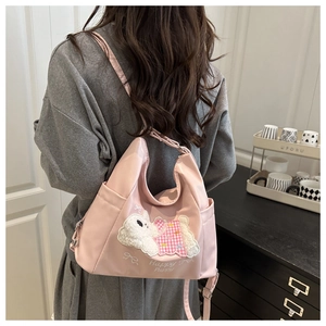 Pink nylon crossbody bag with cute plush puppy patch and adjustable strap on a model