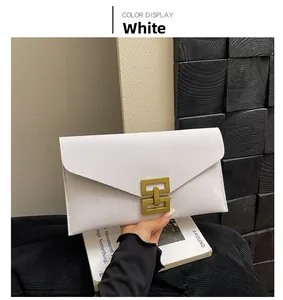 Detail of white envelope clutch bag with gold geometric interlocking lock and textured leather