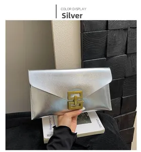 Detail of silver textured envelope clutch bag with a golden geometric metal lock buckle