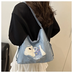 Close-up of light blue canvas tote bag featuring plush puppy applique and embroidery