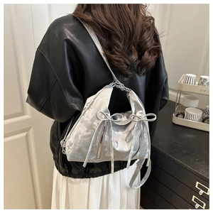 Détail du sac cabas en satin argenté avec nœuds décoratifs et fini métallisé sur modèle