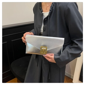 Close-up of a silver cross-grain envelope clutch bag with bronze square metal lock buckle