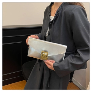 Detail of silver envelope bag with golden clasp worn with charcoal blazer