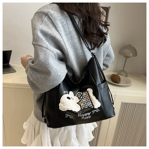 Detail of black tote bag with white puppy embroidery and Happy Puppy ribbon graphic