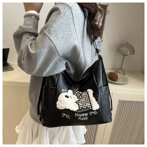Detail of black tote bag featuring a cute white puppy embroidery and functional side pockets
