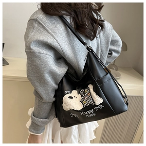 Detail of black PU leather tote bag featuring happy puppy embroidery and 3D applique