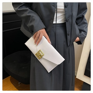 Close-up of a white leather envelope clutch featuring a geometric gold metal fastener