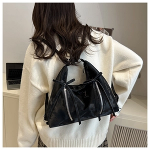 Détail du sac à épaule en satin noir avec nœuds et fermetures éclair sur modèle