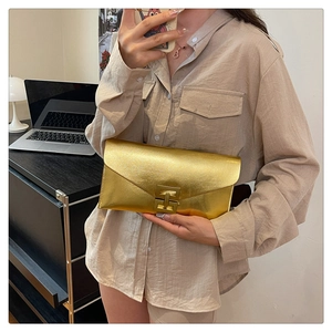Detail of golden envelope clutch bag showing textured brushed finish and metal clasp buckle