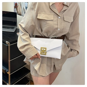 Detailed view of white leather envelope clutch with gold metal interlocking buckle closure
