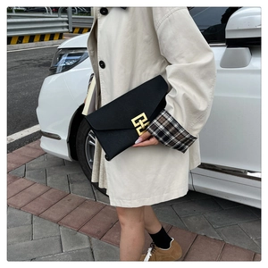 Detail of a black leather envelope clutch bag featuring a golden geometric metal lock