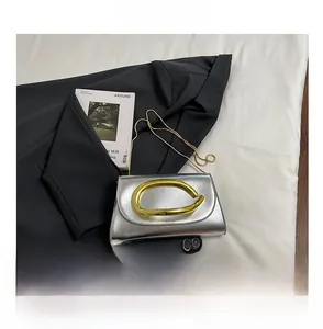 Comparaison de taille de la pochette argentée avec poignée dorée à côté d'un téléphone
