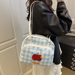 Blue and white checkered shoulder bag with a red apple print shown on a model