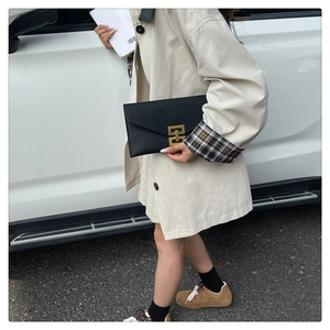Close-up of black grainy leather clutch featuring a stylish gold square metal buckle