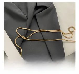 Détail de la bandoulière en chaîne dorée sur une veste noire pour petit sac à main chic