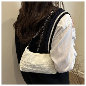Détail d'un sac à bandoulière blanc plissé avec une élégante chaîne en argent pour femme