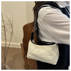 Détail d'un sac à bandoulière blanc plissé avec chaîne porté par un mannequin