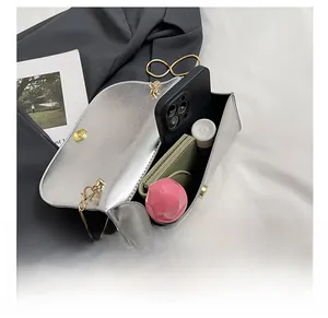 Macro view of silver crossbody bag interior holding a smartphone and makeup items