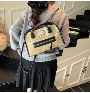 Detail of khaki textured crossbody bag with black trim and silver brand plate on pocket